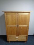 A contemporary oak double door child's wardrobe fitted two drawers beneath