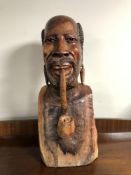 An African carved bust of a man smoking a pipe, height 53cm.