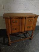 A 20th century carved oak serpentine fronted two drawer chest on raised bobbin legs