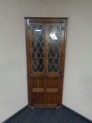 An Ercol elm and beech corner display cabinet with leaded glass doors in an oak finish