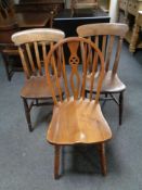 A pair of pine farmhouse kitchen chairs together with a further oak wheel back chair