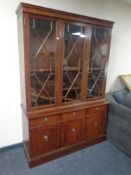A Regency style triple door glazed bookcase fitted cupboards and drawers beneath with lion mask
