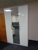 A white gloss triple door wardrobe with central mirror door
