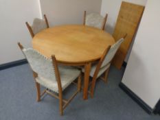 A circular continental oak dining table with extension leaf and a set of four chairs