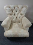 A contemporary high backed button back armchair upholstered in a cream and beige fabric