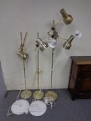 Three continental brass floor lamps together with two further white metal floor lamps