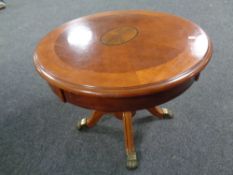 A circular pedestal coffee table on brass capped feet