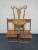 A pair of folding teak garden chairs together with a further chair