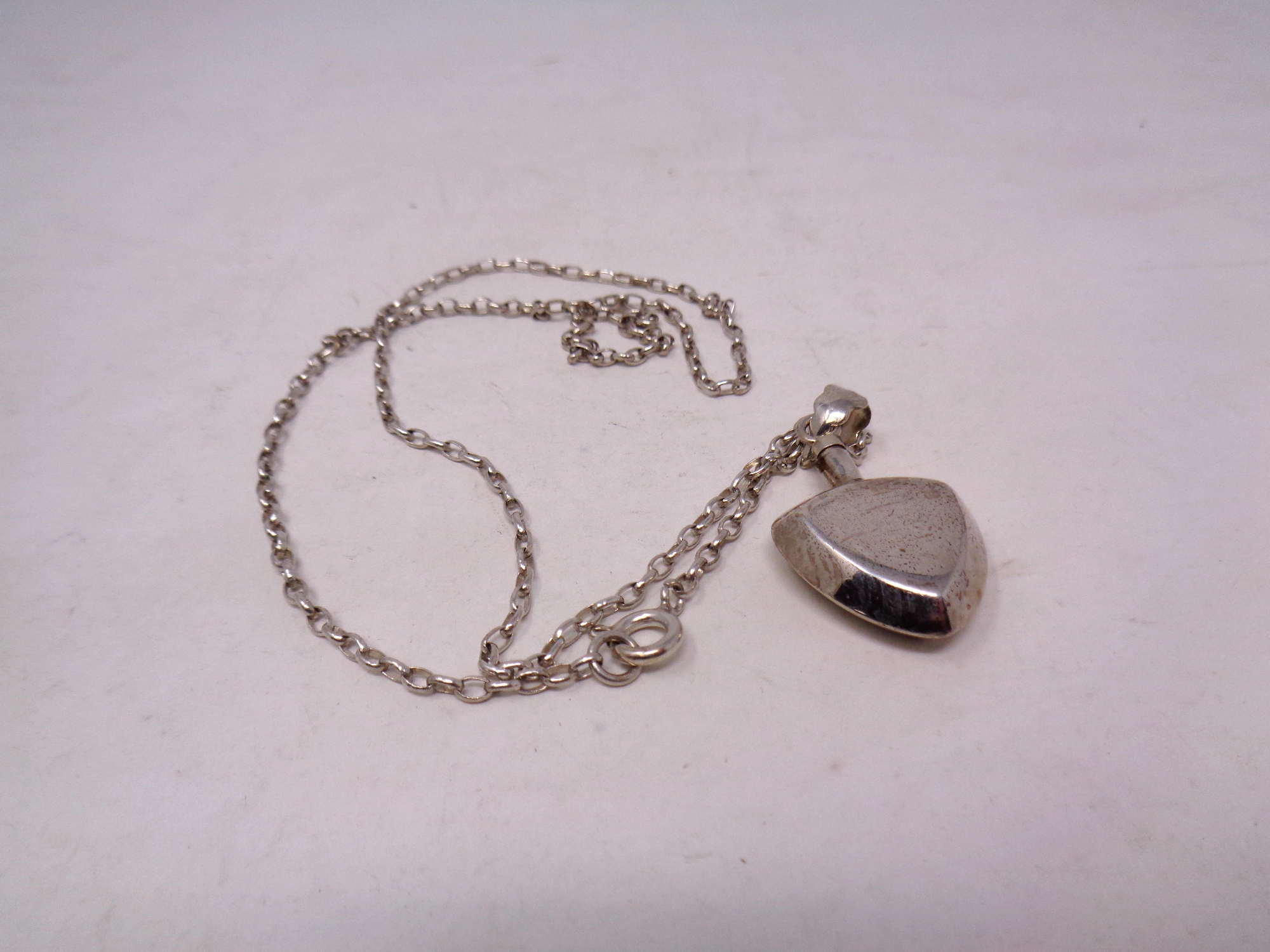 A silver perfume pendant on chain