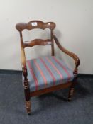 An antique carver armchair in a mahogany finish