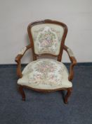 A carved beech framed French salon armchair upholstered in a tapestry fabric