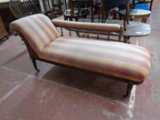 An Edwardian oak framed chaise longue upholstered in a striped fabric with two matching cushions