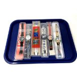 A group of six various Swatch watches in plastic cases.