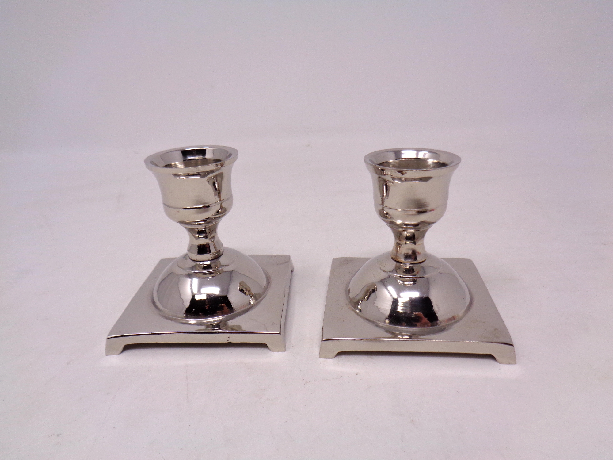 A pair of nickel plated brass candle holders
