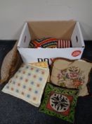 A box containing a woolen throw and tapestry cushions