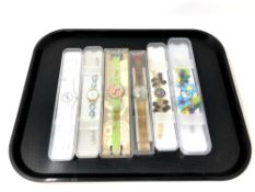 A group of six various Swatch watches in plastic cases.