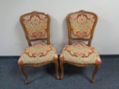 A pair of carved beech French dining chairs on cabriole legs upholstered in a floral fabric