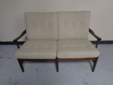 A late 20th century continental stained wood framed two seater settee upholstered in a beige fabric