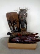 A box containing carved tribal tourist masks and figures