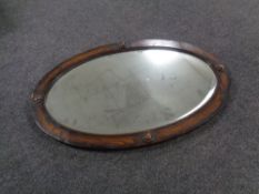 An Edwardian oak oval framed bevel edged mirror