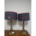 A pair of brass Corinthian column table lamps with tartan shades