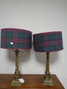 A pair of brass Corinthian column table lamps with tartan shades