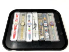 A group of seven various Swatch watches in plastic cases.