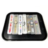 A group of seven various Swatch watches in plastic cases.