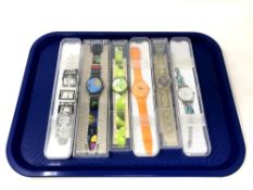 A group of six various Swatch watches in plastic cases.