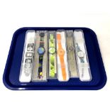 A group of six various Swatch watches in plastic cases.