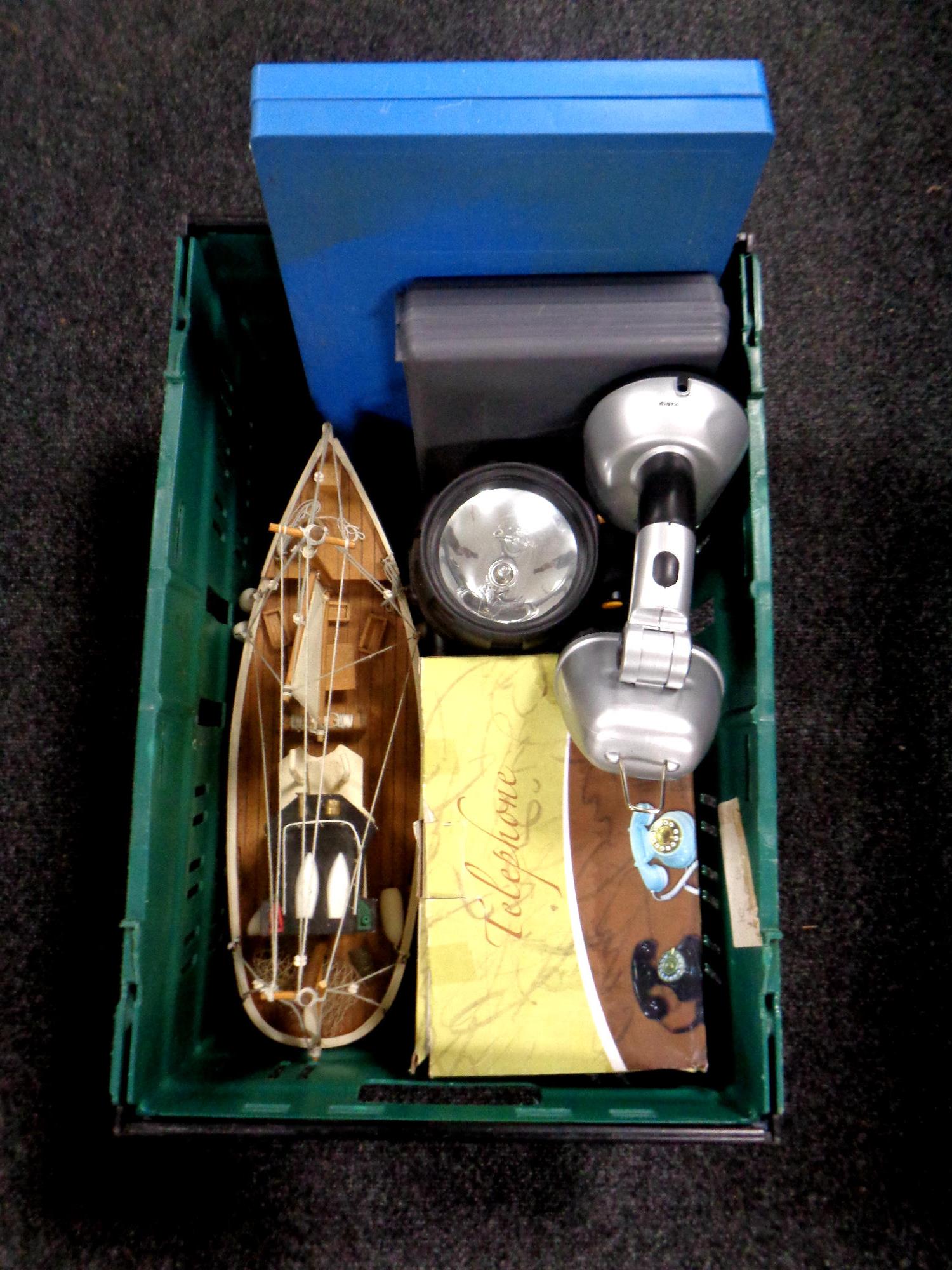 A crate containing cased Xylophone, boxed retro style telephone, wooden model of a trawler,