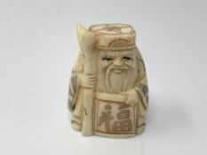 A carved Chinese bone netsuke - Gentleman carrying a scroll