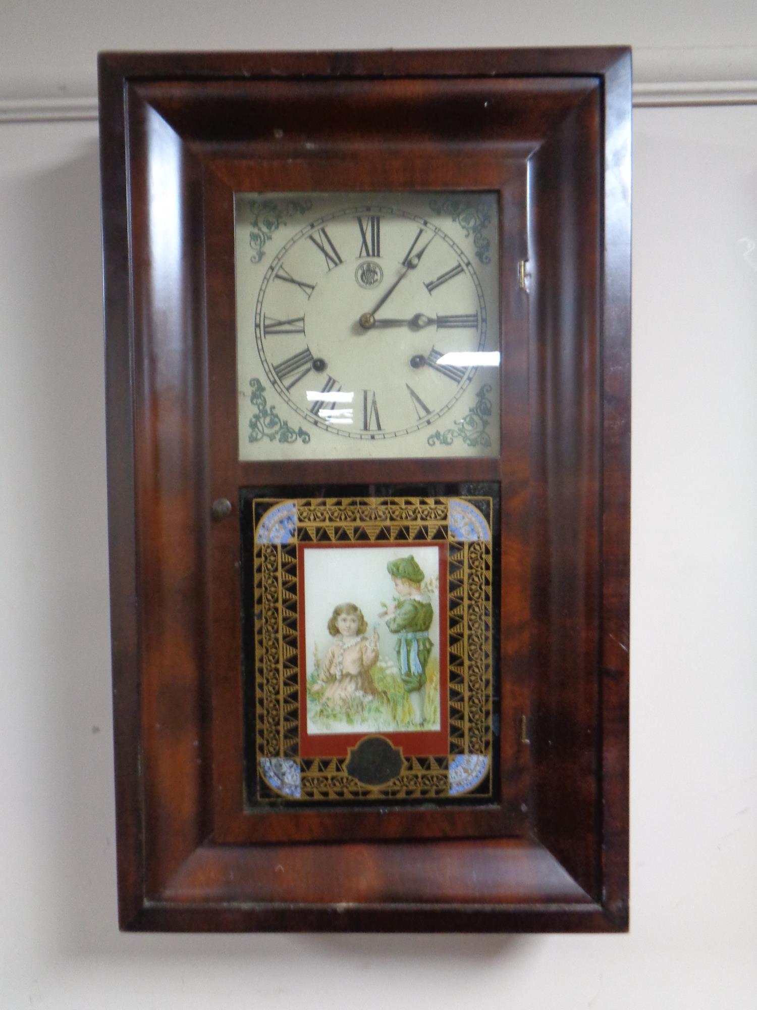 An antique American Water Bury 30 hour wall clock with glass panel depicting two children in a