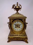 An ornate nineteenth century brass mantel clock with brass and enamel dial surmounted by a twin