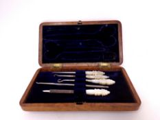 A part walnut case of mother of pearl sewing items.