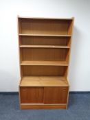 A set of teak effect open bookshelves with sliding double door cupboard beneath