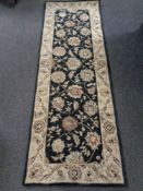 A Gooch New Zealand floral rug on black ground, 178cm by 61cm.