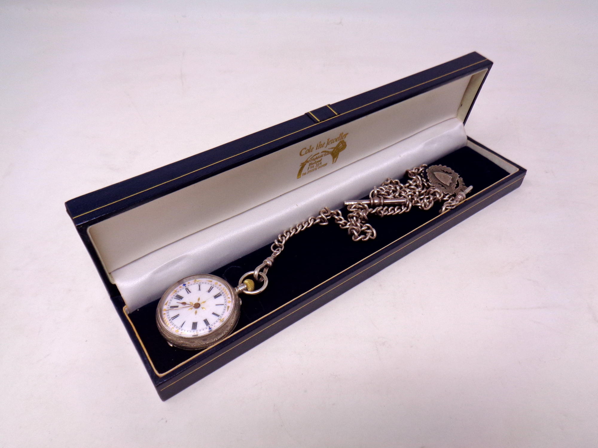 A silver fob watch on Albert chain
