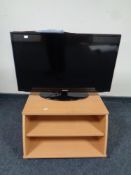 A Samsung 32" LCD TV with remote together with a DVD player and remote on three tier pine TV