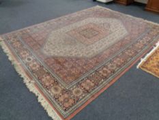 A machine made Persian design fringed carpet on pink ground,