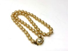A cultured pearl necklace with yellow metal clasp,
