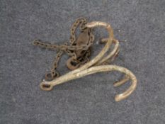 An antique cast iron ship's anchor and a pulley on chain