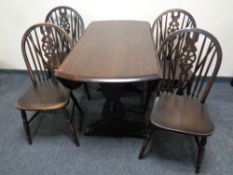 An Ercol solid elm and beech drop leaf table together with a set of four wheel back chairs in an