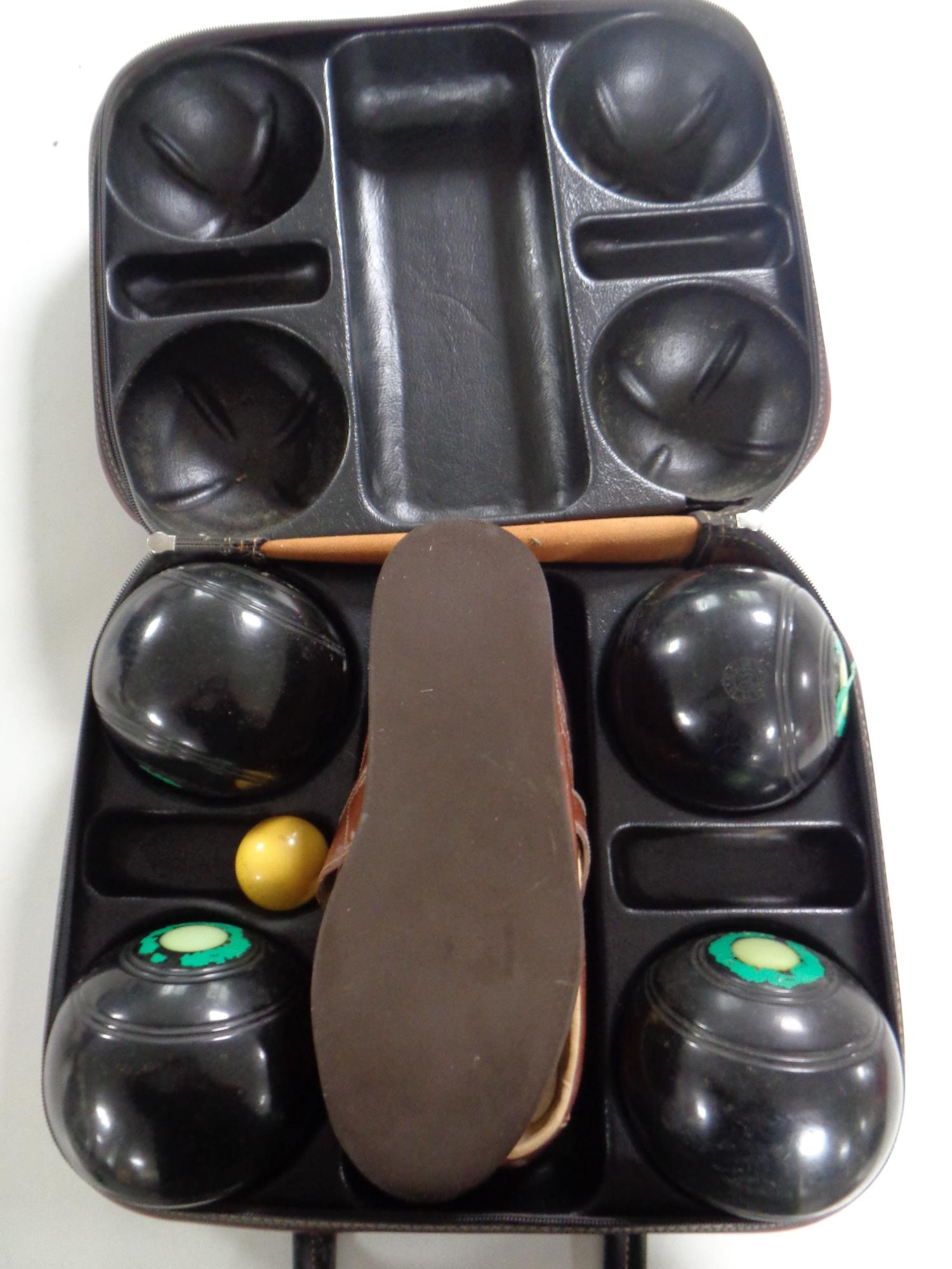 A leather case of a set of four Taylor lawn bowls and a pair of bowling shoes