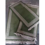 Three matching fringed woolen rugs on green ground