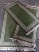 Three matching fringed woolen rugs on green ground