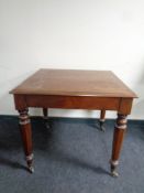 A 19th century square kitchen table on brass casters