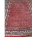 A fringed Persian carpet on red ground 218 cm x 310 cm.