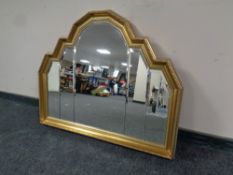 A decorative shaped gilt framed bevel edged sectional mirror