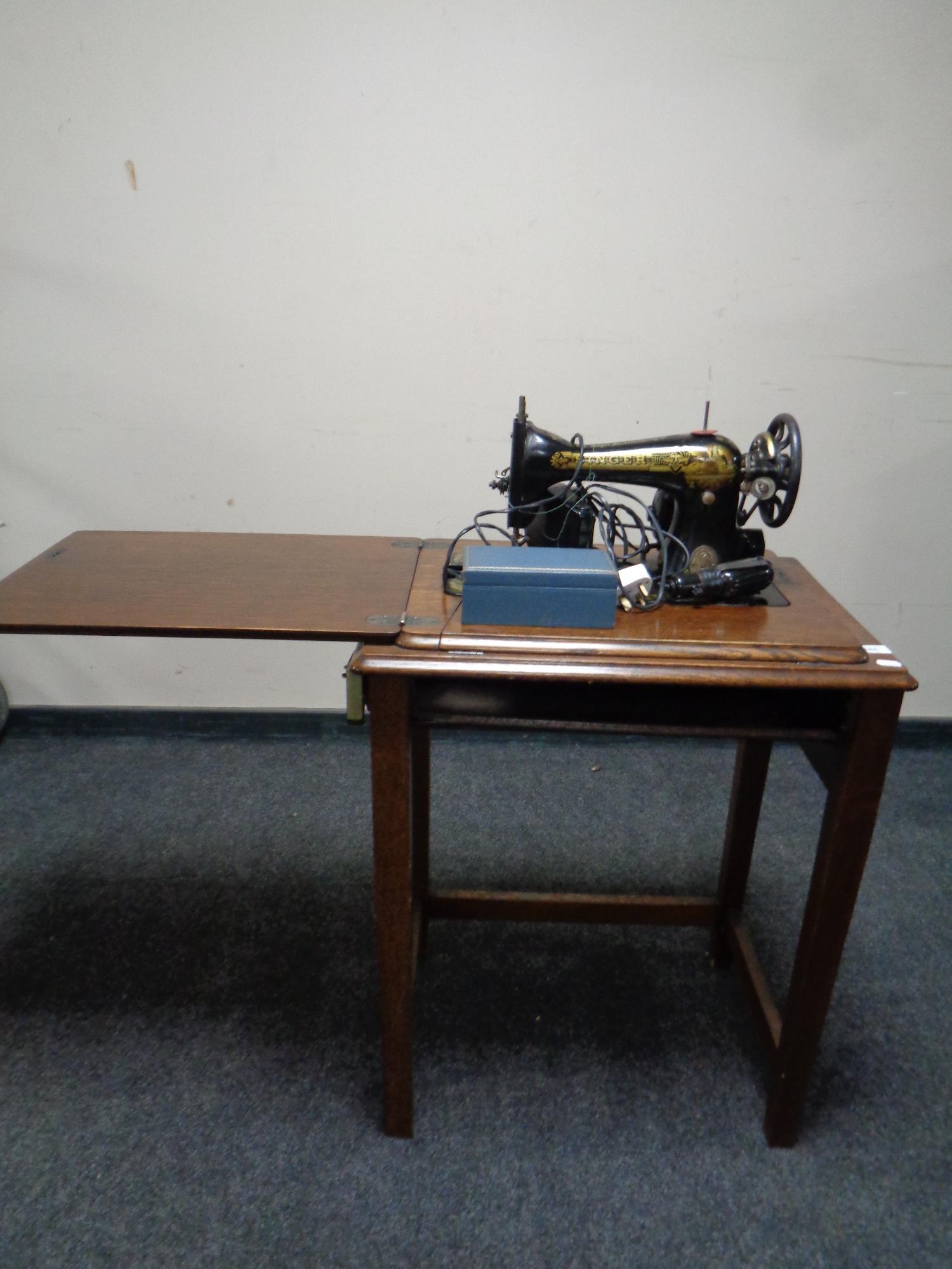 A 20th century Singer electric sewing machine in oak table